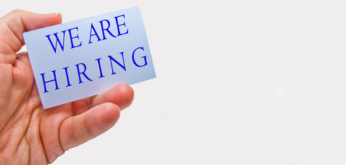 Job recruiting advertisement represented by 'WE ARE HIRING' texts on cards in man's hands