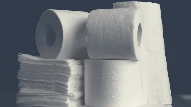 Rotating stack of paper rolls, paper tissue, napkins. White hygienic disposables on black background. Body care products. Kitchen disposables. Foggy