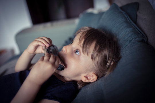 Blond girl playing harmonica while lying on sofa at home