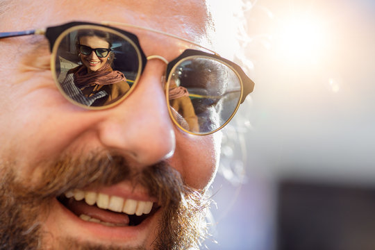 Smiling man in sunglasses with reflection of woman