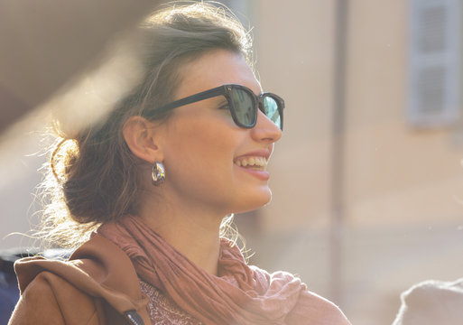 Smiling brunette woman in eyeglasses standing outdoors