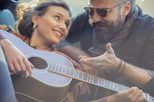 Man looking at woman playing guitar