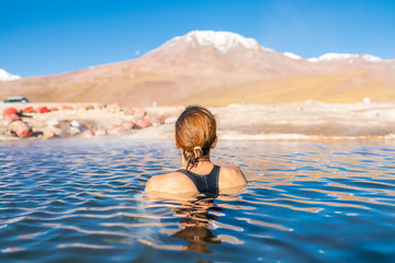 Woman taking a bath at El Tatio Geysers hot springs at Atacama desert, amazing thermal spring waters at 4500 masl inside Andes mountains scenic a place with an awe geothermal activity below the ground - obrazy, fototapety, plakaty
