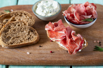 coppa di parma meat, cream cheese and ciabatta bread on wooden surface
