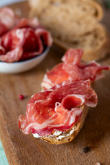 coppa di parma meat, cream cheese and ciabatta bread on wooden surface
