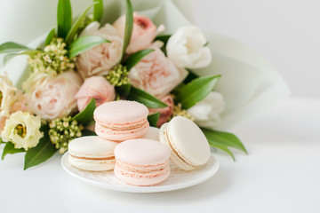 Fototapeta na wymiar Elegant sweet macarons and pastel colored beige flowers