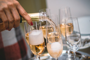 Pouring sparkling yellow champagne on wine glasses