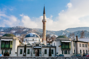 A minaret rises over buildings across the river from the Old Town neighborhood of Sarajevo. Gazi Husrev-bey Mosque.  Bosnia Herzegovina