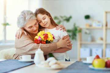 Happy mother's day! granddaughter gives flowers and congratulates an grandmother on holiday .