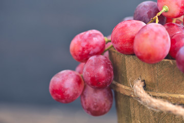 Rose grapes in wooden bucket on a woden table