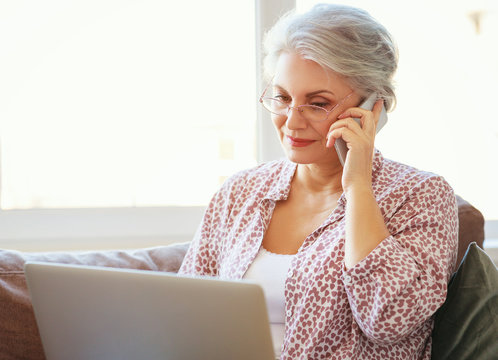 happy old woman senior working at computer laptop at home