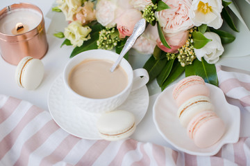 Elegant sweet dessert macarons, cup of coffee and pastel colored beige flowers bouquet