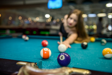 Young and beautiful woman in pub playing billiard