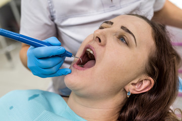 Dentist's hands in gloves with tool and woman face