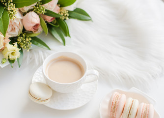 Elegant sweet dessert macarons, cup of coffee and pastel colored beige flowers bouquet