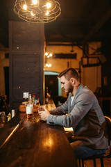 Man with bottle of alcohol at wooden bar counte