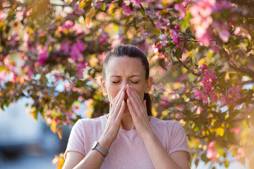 Woman sneezing because of spring pollen allergy