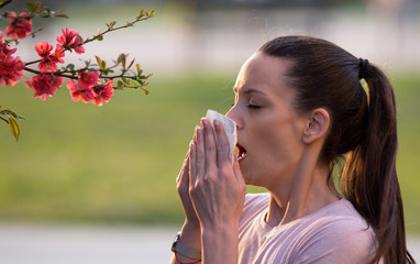 Woman sneezing because of spring pollen allergy