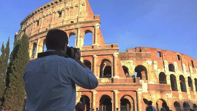 Man takes pictures of Colosseum Rome under the blue serene sky