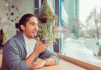 Latin american young adult using voice recognition at phone.