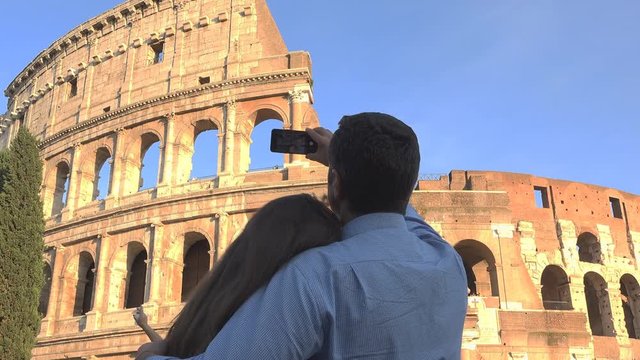 Couple of man and woman embrace take picture to colosseum in rome, love  and blue serene  sky