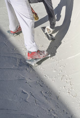 Worker Wearing Spiked Shoes Smoothing Wet Pool Plaster With Trowel
