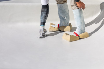 Worker Wearing Sponges On Shoes Smoothing Wet Pool Plaster With Trowel