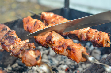 Grilled kebab frying on metal skewers. Roasted meat cooked at barbecue with smoke. Close up