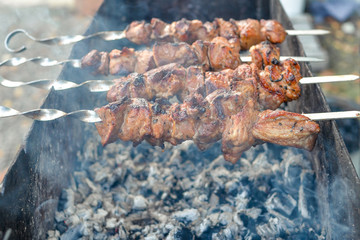 Grilled kebab frying on metal skewers. Roasted meat cooked at barbecue with smoke. Close up
