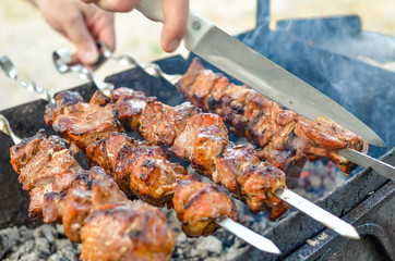 Grilled kebab frying on metal skewers. Roasted meat cooked at barbecue with smoke. Close up