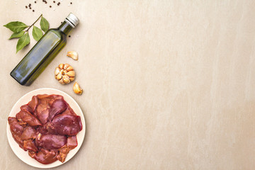 Raw chicken liver with spices on a stone background. Garlic, olive oil, black pepper, bay leaf, top view, copy space.