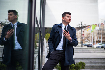 Confident businessman using phone near office building