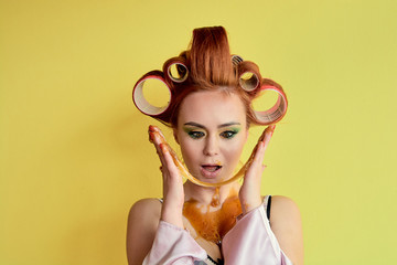 Young redhead woman with shugaring paste on her hands, face, body and chest. Young redhead woman with hair curlers. Advertising concept of shugaring paste. Skin care concept with copyspace.