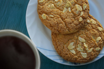 Cup of tea and saucer with two cookies with nuts on the blue table. Top view. Close up.