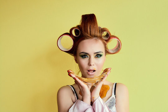Young redhead woman with shugaring paste on her hands, face, body and chest. Young redhead woman with hair curlers. Advertising concept of shugaring paste. Skin care concept with copyspace.