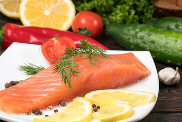 Fresh salmon fish with lemon and salad leaves on wooden table