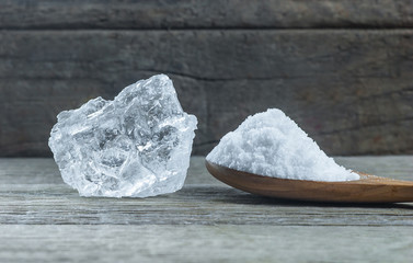 Pure natural white crystal bath or rock salt with food or sea salt in wooden spoon on wooden background