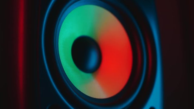 Close up of colorful loud bass speaker vibration on black background