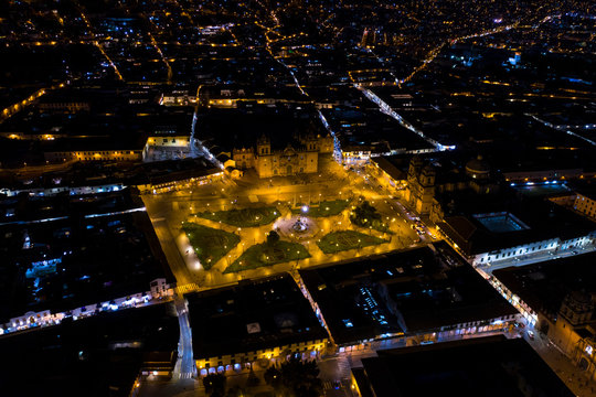 Aerial view of Cusco's main square 'Plaza de Armas' at night. Lively urban gathering place at evening offering colonial arcades, a cathedral and gardens. City located in the Andean mountains of Peru.