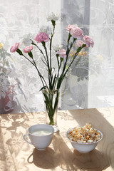 A mug of milk and a cup with popcorn on a sunny table, a bouquet of spring flowers for mood, diet food and a healthy lifestyle in the village, the perfect morning in the village