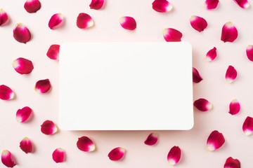 top view of red rose petal with white card