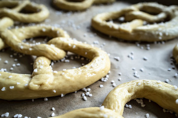 Raw pretzels with coarse salt are placed on a metal tray and are ready for baking in the oven. Traditional food. Oktoberfest.
