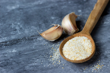 Ground garlic spice in the wooden spoon, seasoning dishes, using spices  for meals.