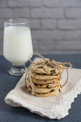 A gift stack of healthy dried cherry cookies tied in a bow with twine on a napkin edged in lace sitting on a blue countertop with a glass of milk. Cherries have antioxidants, and are Anti-Inflammatory