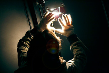 Man manipulating spot light with gloves in production studio for shooting a movie. Reflector and...