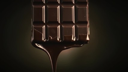 Chocolate bar with melted dark chocolate dripping over dark brown background. Confectionery concept backdrop. Melted premium chocolate flowing. Sweet dessert. 4K UHD video, slow motion