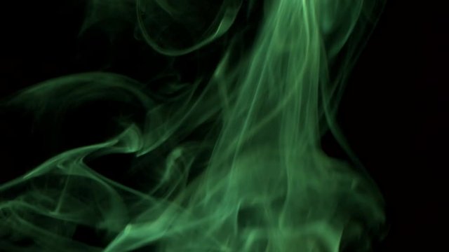 Clouds of bright green moke billow rising swirl up. Cigar smoke blowing to top. Closeup, isolated on black background.