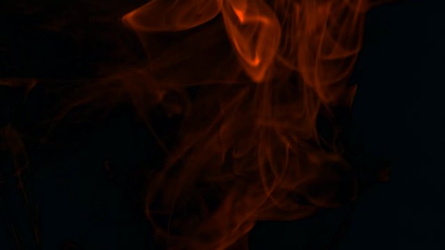 Clouds of fiery red smoke billow rising swirl up, isolated on black background. Cigar smoke blowing to top. Closeup.