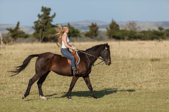 Attractive young blonde woman riding her horse