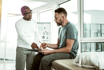 Obraz premium Handsome young therapist pointing at important document